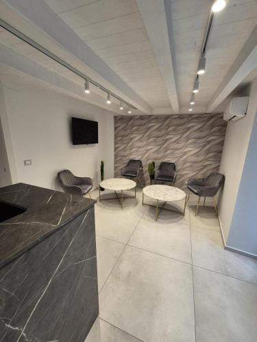 a waiting room with chairs and tables and a tv at La Maison de Rosaline Rooms in Barletta