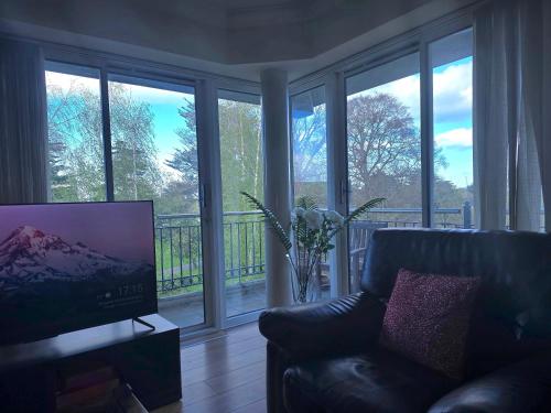 a living room with a couch and a tv and windows at Gracian OMB Dublin Apartment in Dublin
