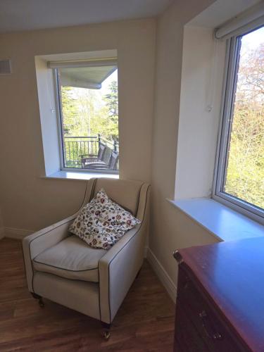 a chair with a pillow sitting in a room with two windows at Gracian OMB Dublin Apartment in Dublin