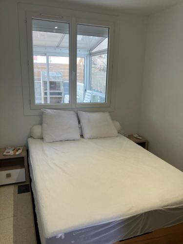 - un lit avec deux oreillers dans une chambre avec deux fenêtres dans l'établissement Appartement 4 personnes St-Pierre-la-Mer proche commerces, à Fleury