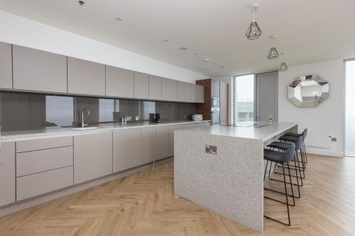 a kitchen with white cabinets and a island with bar stools at Greengate in Manchester