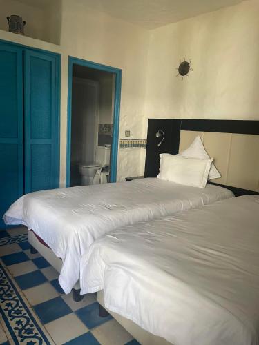 a bedroom with two beds and a bathroom with a toilet at Riad Al Madina in Essaouira