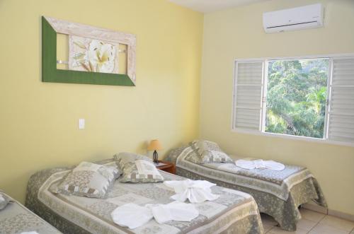 two twin beds in a room with a window at Hotel Chapadao Da Canastra in São Roque de Minas
