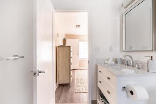 a white bathroom with a sink and a mirror at Delray Oasis: Pool, Gazebo & Beach Access in Delray Beach