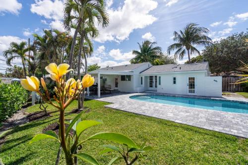 a house with a swimming pool and palm trees at Delray Oasis: Pool, Gazebo & Beach Access in Delray Beach
