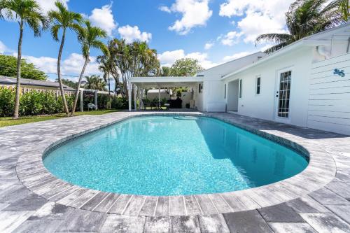 a swimming pool in the backyard of a house with palm trees at Delray Oasis: Pool, Gazebo & Beach Access in Delray Beach