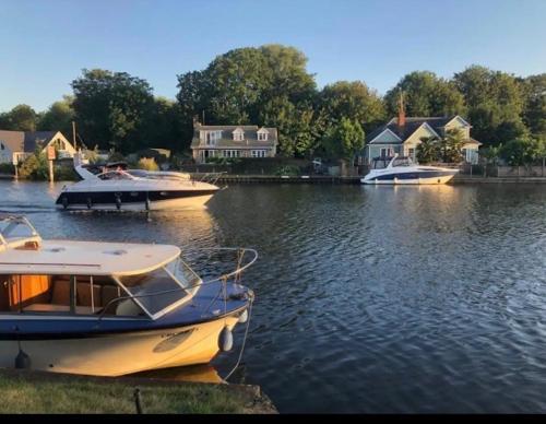 three boats are docked in a river with houses at Serene spacious room (double) in gorgeous bungalow on river near Thorpe park and Holloway University Egham in Staines upon Thames