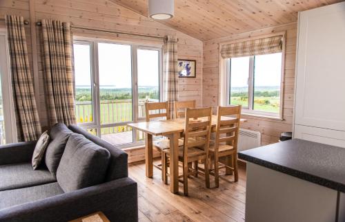 a living room with a couch and a table and chairs at Burgie Woodland Lodges in Forres