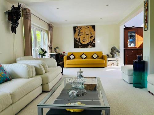a living room with a couch and a table at Serene spacious room (double) in gorgeous bungalow on river near Thorpe park and Holloway University Egham in Staines upon Thames