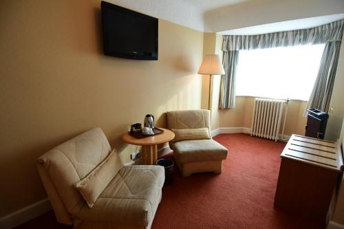 a hotel room with two chairs and a table and a tv at The Trouville Bournemouth in Bournemouth