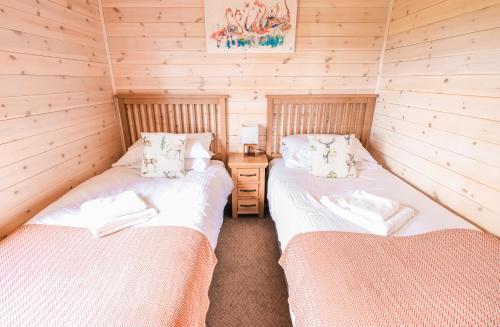 two beds in a room with wooden walls at Burgie Woodland Lodges in Forres