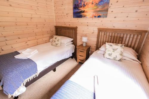 a bedroom with two beds in a log cabin at Burgie Woodland Lodges in Forres