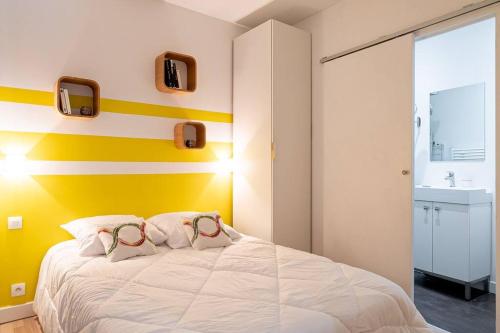 - une chambre dotée d'un lit avec un mur jaune et blanc dans l'établissement L'Acapulco, Charmant T1, Clim, Place Comédie, à Montpellier