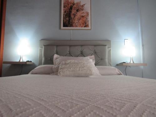 a bedroom with a white bed with two lamps at Apartamento Rincon sereno in Medellín