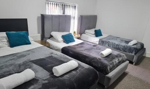 a room with three beds with blue and white pillows at Tudors eSuites Budget Apartments in Birmingham