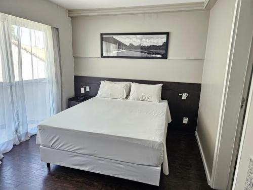 um quarto com uma cama branca num quarto em Flat Pampulha orla prox Mineirão em Belo Horizonte