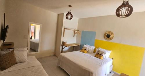 a bedroom with a bed and a mirror at Chalés Mar e Sol in São Miguel do Gostoso