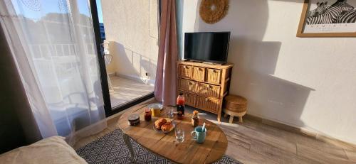 ein Wohnzimmer mit einem Couchtisch und einem TV in der Unterkunft Terrasses 2 - Plage et commerces à 400 m in Le Grau-du-Roi