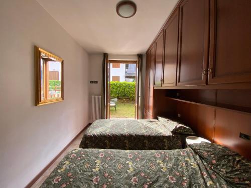 Un dormitorio con dos camas y un espejo y una ventana. en Tiny House Valbondione [wi-fi], en Valbondione