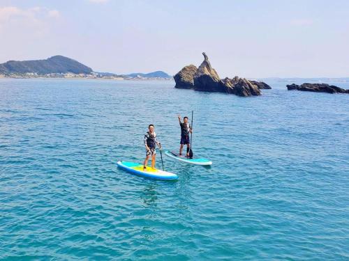 two people are standing on paddle boards in the water at Sea Front Villa in Tateyama