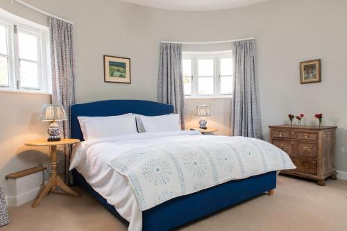 a bedroom with a blue bed and two windows at The Hop Kiln in Leominster