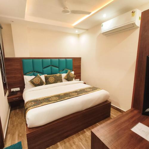 a bedroom with a large bed with a green headboard at Hotel East Wood Amritsar in Amritsar