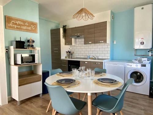 une cuisine avec une table et des chaises et une cuisine aux murs bleus dans l'établissement L'horizon, à 100 mètres de la mer, à Le Portel