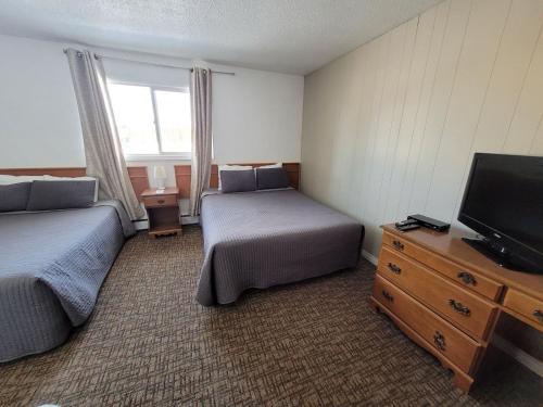 um quarto de hotel com duas camas e uma televisão em GRIZZLY MOTEL em Swan Hills