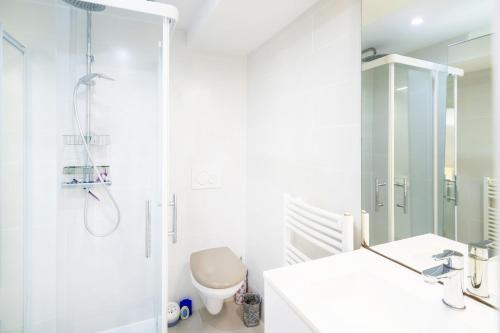 La salle de bains blanche est pourvue d'une douche et de toilettes. dans l'établissement Appartement de charme - spa privé, à Biarritz