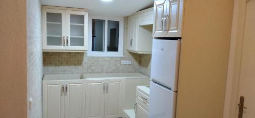 a kitchen with white cabinets and a white refrigerator at Villa Askim in Sogut