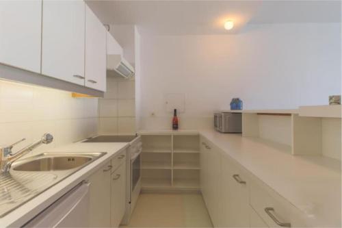 een witte keuken met witte kasten en een wastafel bij Lichtrijke studio in Kortrijk