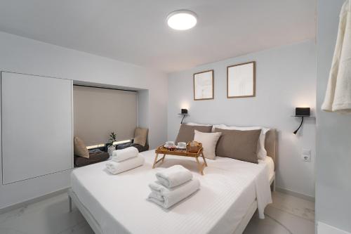 una camera da letto bianca con un grande letto bianco con asciugamani sopra di Aelia Elegant Apartments a Kalamáta