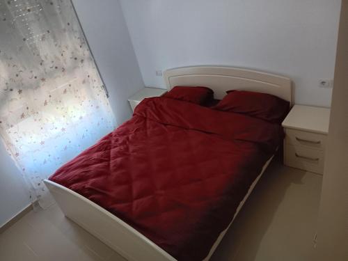 a bed with a red comforter in a room at Diamond Hill Apartment in Vlorë