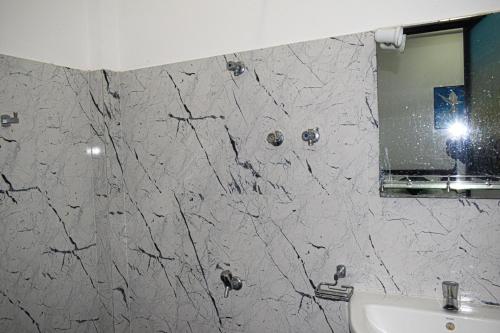 a bathroom with a marble wall with a mirror and a sink at Orr's Hill Sea Side in Trincomalee