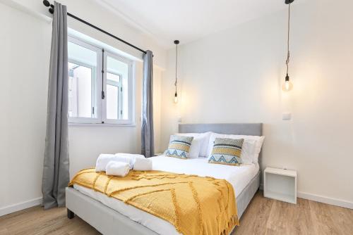 a bedroom with a bed with a yellow blanket on it at Largo da Estação Apartments By Sé Apartamentos in Braga