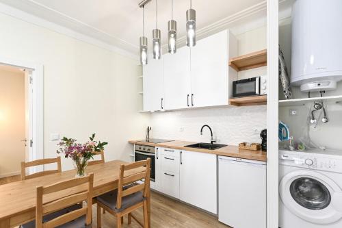 a kitchen with white cabinets and a wooden table at Largo da Estação Apartments By Sé Apartamentos in Braga