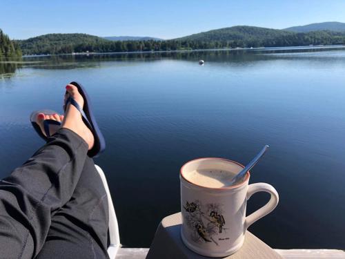 eine Person, die auf einem Boot mit einer Tasse Kaffee sitzt in der Unterkunft Chalet Le Pélican in Lac-Superieur