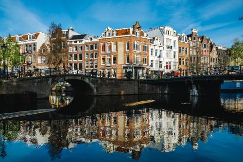 a bridge over a river in a city with buildings at Amsterdam Wiechmann Hotel in Amsterdam