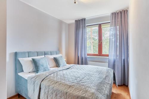 a bedroom with a blue bed with a window at Apartamenty Świnoujście - Rezydencja Żeromskiego in Świnoujście