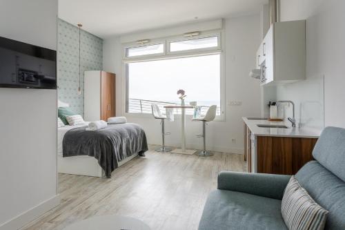 a bedroom with a bed and a kitchen with a window at APARTAMENTOS KRESALA - Vistas al mar in Getaria