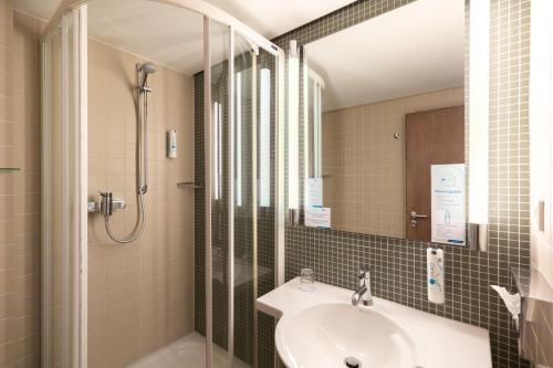 a bathroom with a sink and a shower at Select Hotel Silence Garden Köln in Cologne