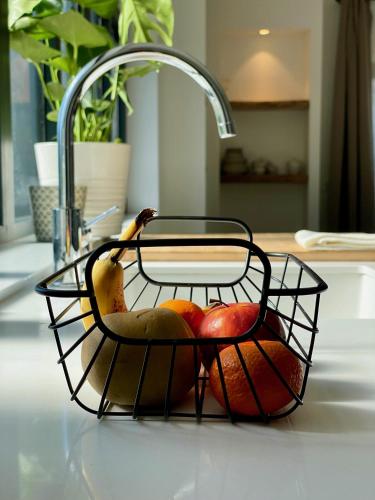 une corbeille de fruits assise sur un comptoir à côté d'un évier dans l'établissement Maison avec terrasse privée proche Disneyland Paris, à Lesches