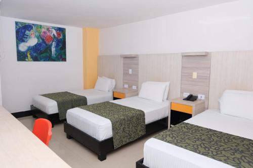a hotel room with three beds and a painting on the wall at Hotel Genova Prado in Barranquilla