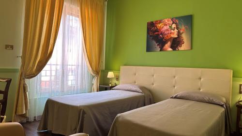 a green room with two beds and a window at Hotel Roma in Bologna