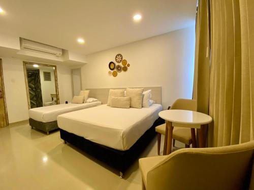 um quarto de hotel com duas camas e uma mesa em Hotel Dorado Plaza Bocagrande em Cartagena das Índias