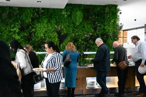 a group of people standing around a counter with food at Royal G Max in Golem