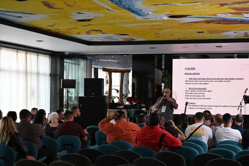 a man giving a presentation to a crowd of people at Royal G Max in Golem