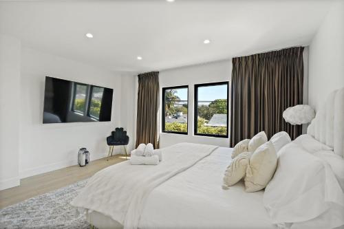 um quarto branco com uma grande cama branca e janelas em Modern Luxurious Dream Home Mar Vista, 4BDRMs, 4Baths, Kid & Pet Friendly, 10min to the beach!! em Los Angeles