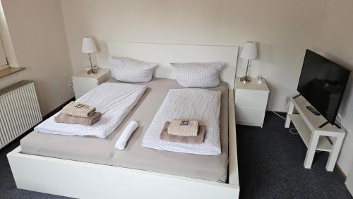 a white bedroom with two beds and a flat screen tv at Hotel Dorfkrug Büsum - günstige Altbauzimmer Am Oland in Büsum