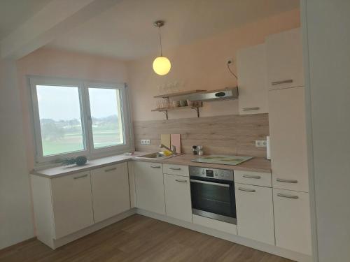a kitchen with white cabinets and a window at Apartment Panoramablick in Klopein am Klopeiner See